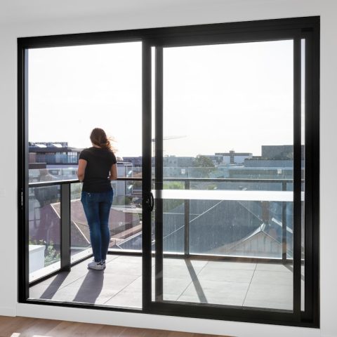 woman in blue denim jeans standing near glass window during daytime