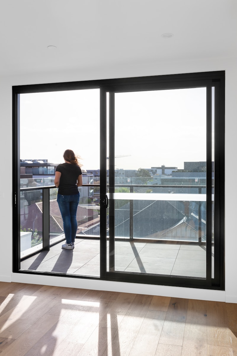 woman in blue denim jeans standing near glass window during daytime