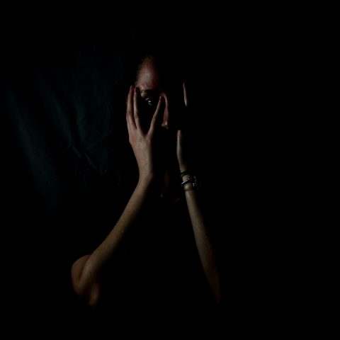 woman holding her face in dark room