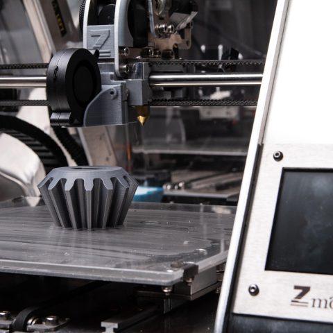 Een FDM 3D printer in een werkplaats die een plastic onderdeel print