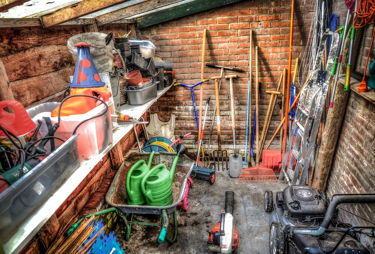 Binnenkant van een houten tuinhuis met gereedschap aan de wand en een houten vloer