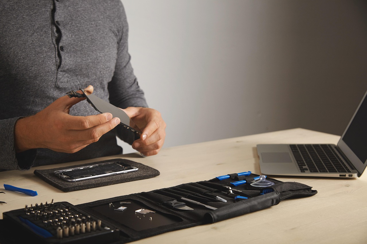 Een kapotte laptop op een werkbank naast een set reparatietools